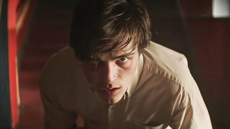 Jacob Elordi as Jake Matthews in The Mortuary Collection, leaned down while facing the camera, head turned upward and looking past the lens.