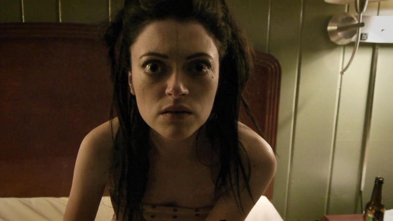 Hannah Fierman as Lily in V/H/S, sitting on a bed and she looks dead on just past the camera.