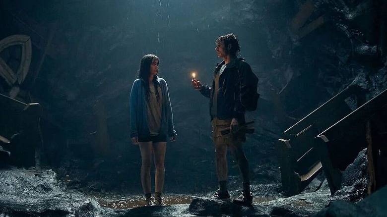 Alison Brie as Millie Wilson and Dave Franco as Tim Brassington, standing in a cave in Together.