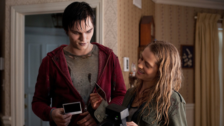 Nicholas Hoult as R and Teresa Palmer as Julie, laughing and looking at polaroids in Warm Bodies.