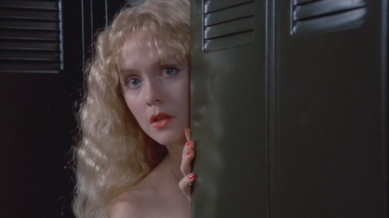 Wendy Lyon as Vicki Carpenter in Hello, Mary Lou: Prom Night II, peeking around the corner of lockers and looking at something with concern.