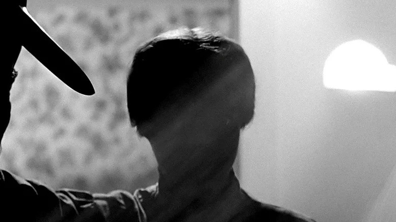 Norman Bates (Anthony Perkins), dressed as his mother, raises a knife in Psycho (1960)