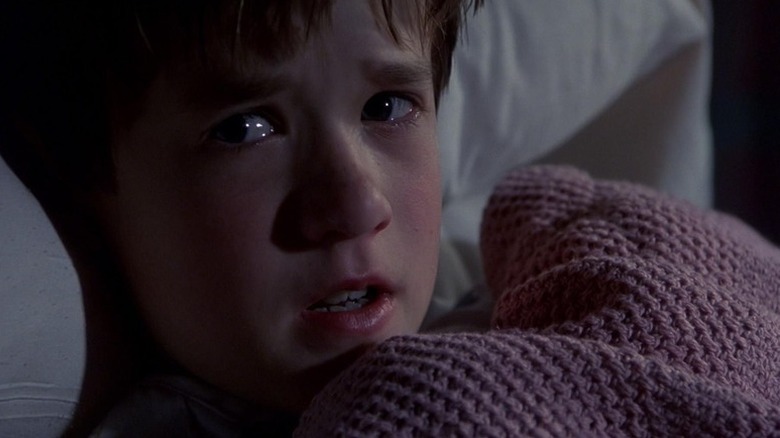 Cole Sear (Haley Joel Osment) cowers under a blanket in The Sixth Sense