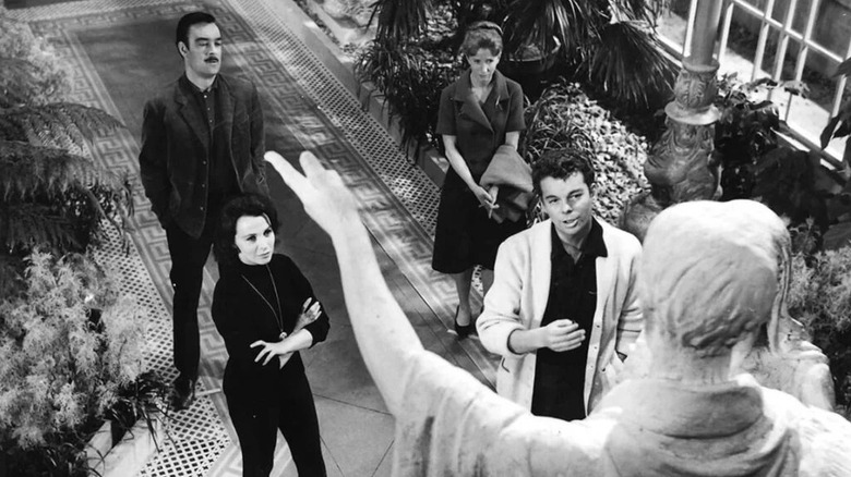 Richard Johnson as Dr. John Markway, Claire Bloom as Theo, Julie Harris as Eleanor "Nell" Lance, and Russ Tamblyn as Luke Sanderson in The Haunting, seen standing before a classical statue.
