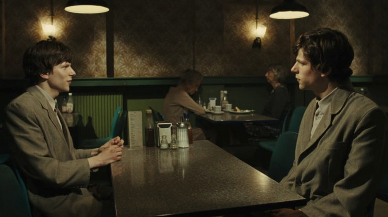 Jesse Eisenberg as Simon James looking at Jesse Eisenberg as James Simon at a table in a diner in The Double