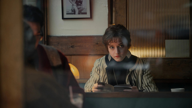Julia Garner as Terry Gionoffrio, sitting at a table reading in Apartment 7A