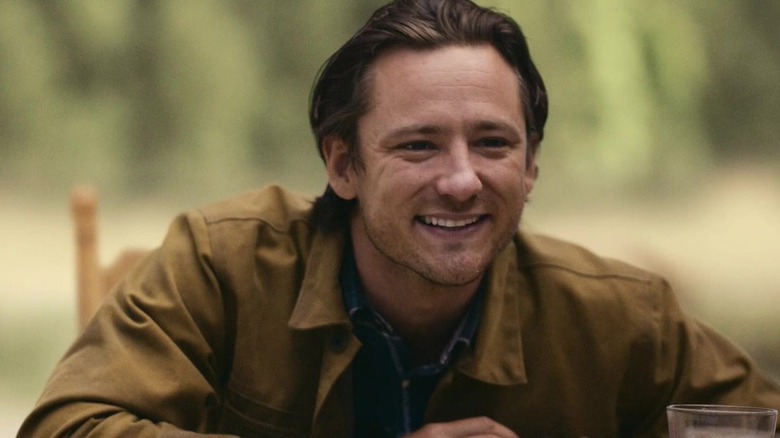 Lewis Pullman as Rhett Abbott smiling outside in Outer Range
