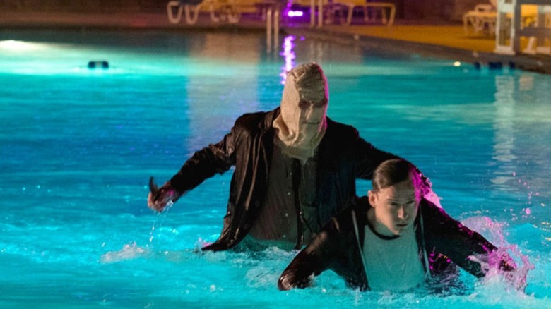 Lewis Pullman as Luke being chased by a masked killer in a pool in The Strangers: Prey at Night