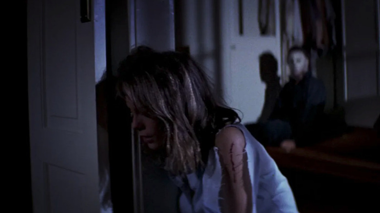 Nick Castle as The Shape (Michael Myers) sits up behind an injured Laurie Strode (Jamie Lee Curtis) in Halloween (1978)
