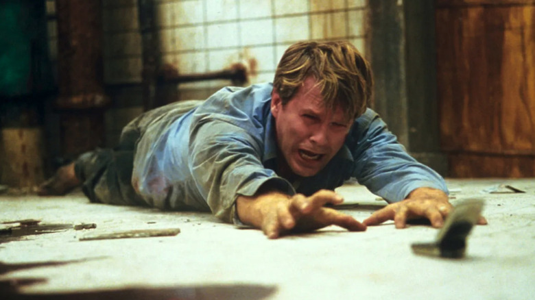Cary Elwes as Lawrence Gordon reaching for a cell phone in a dirty bathroom in Saw (2004)