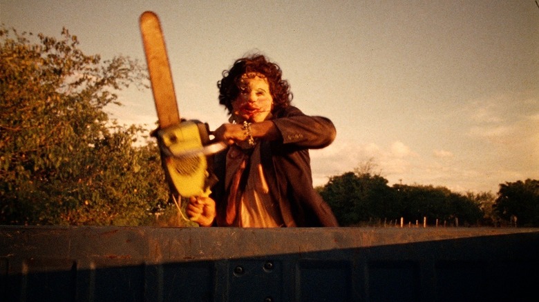 Gunnar Hansen as Leatherface in The Texas Chain Saw Massacre, wielding his chainsaw and looking toward the camera.