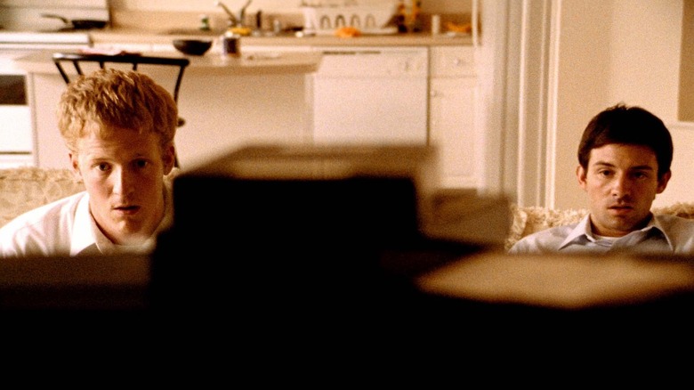 Shane Carruth as Aaron and David Sullivan as Abe in Primer, seen from the perspective of a television that they're sitting on a couch watching.