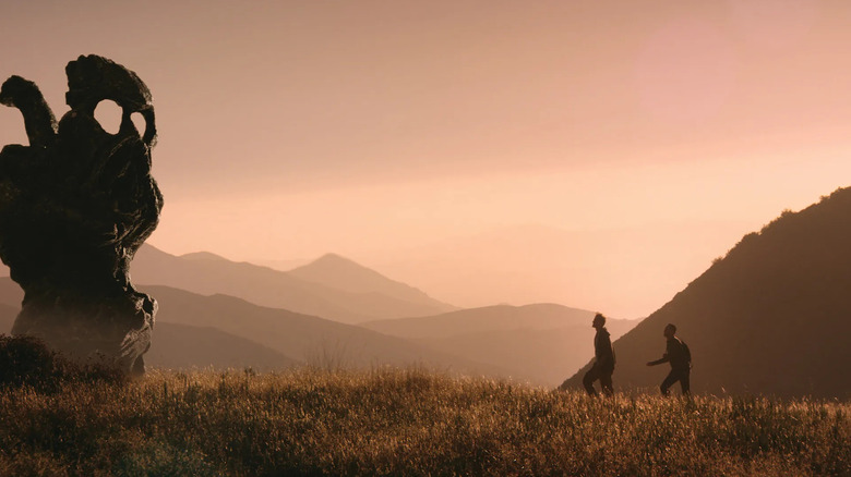 Justin Benson as Justin Smith and Aaron Moorhead as Aaron Smith in The Endless, walking through a valley up to a strange rock formation.