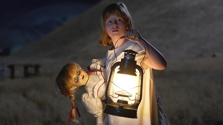 Linda (Lulu Wilson) holding a lamp and Annabelle doll in Annabelle: Creation