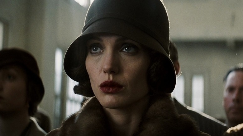 Angelina Jolie as Christine Collins in Changeling, sitting in a room with other people behind her and looking slightly up toward something past the frame.