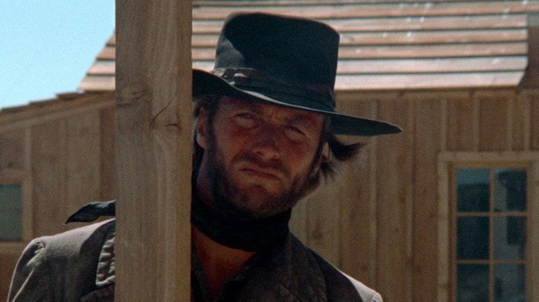 Clint Eastwood as The Stranger in High Plains Drifter, standing behind a post with his cowboy gear on.