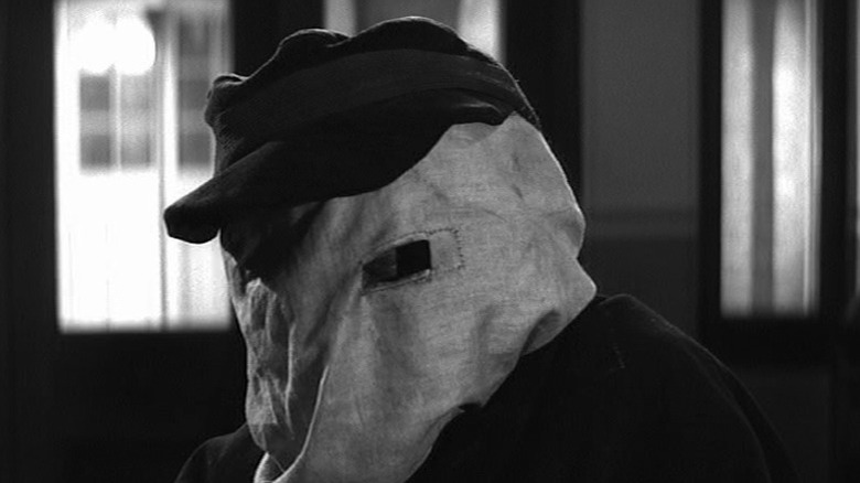 John Hurt as John Merrick with his face covered by a hood in The Elephant Man