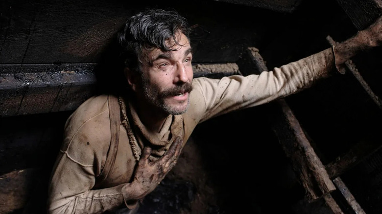 Daniel Day-Lewis as Daniel Plainview, looking up into light from a well in There Will Be Blood.