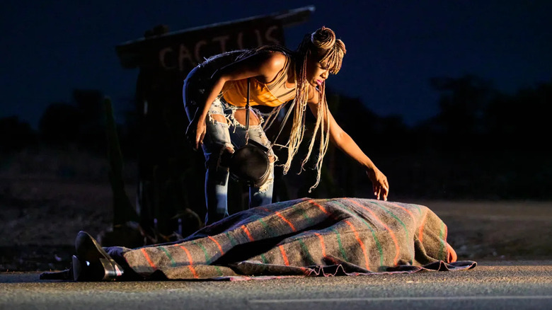 Shula touching a covered dead body on the road in On Becoming a Guinea Fowl