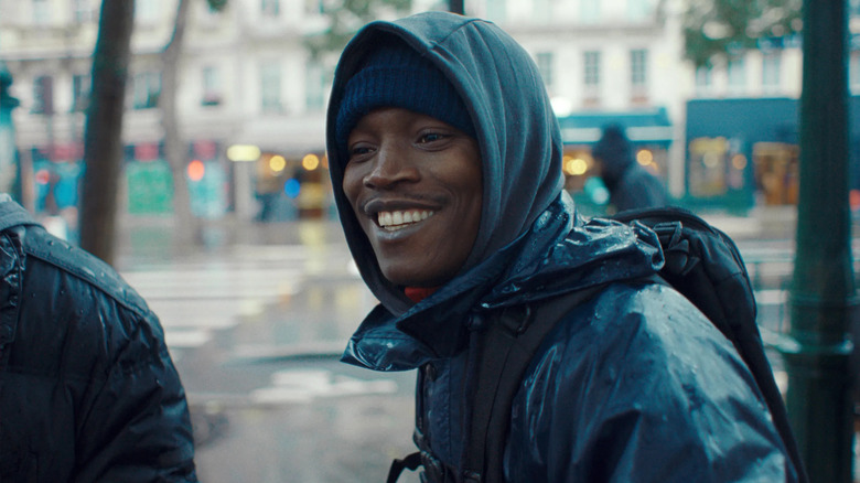 Souleymane smiling on the street in Paris in Souleymane's Story