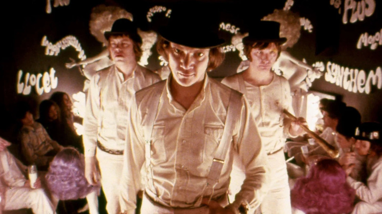 Malcolm McDowell as Alex DeLarge, standing with his droogs in front of people in A Clockwork Orange.