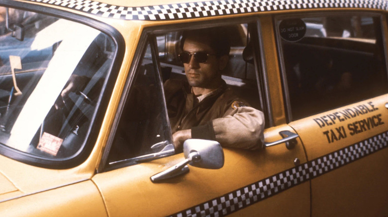 Robert De Niro as Travis Bickle, sitting behind the wheel of a taxi in Taxi Driver.