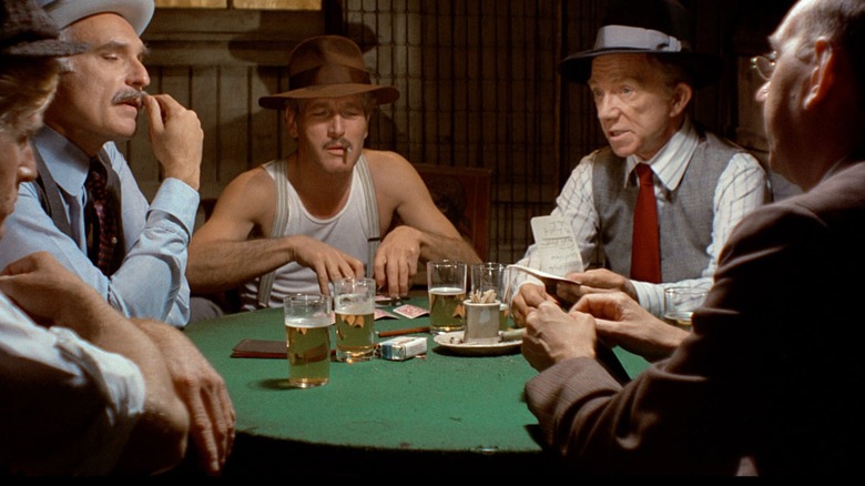 Four men sit around a poker table with cards and drinks in The Sting.