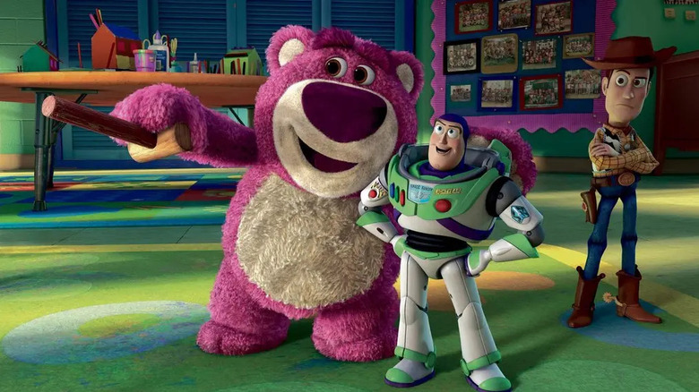 Large pink bear holding mallet next to Buzz Lightyear and Woody on colorful carpet in Toy Story 3