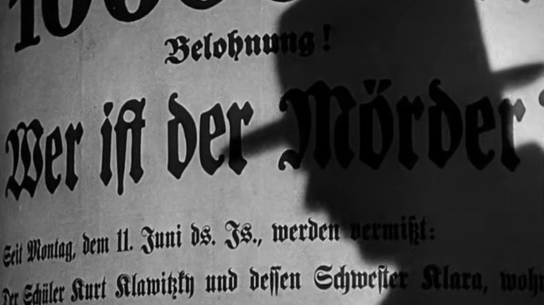 A man's shadow cast on a wanted poster in M