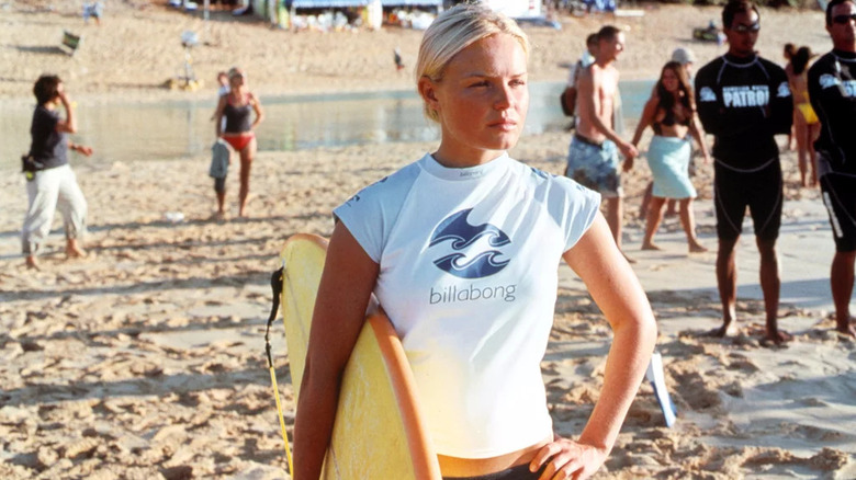 Kate Bosworth as Anne Marie standing on the beach holding a yellow surfboard in Blue Crush.