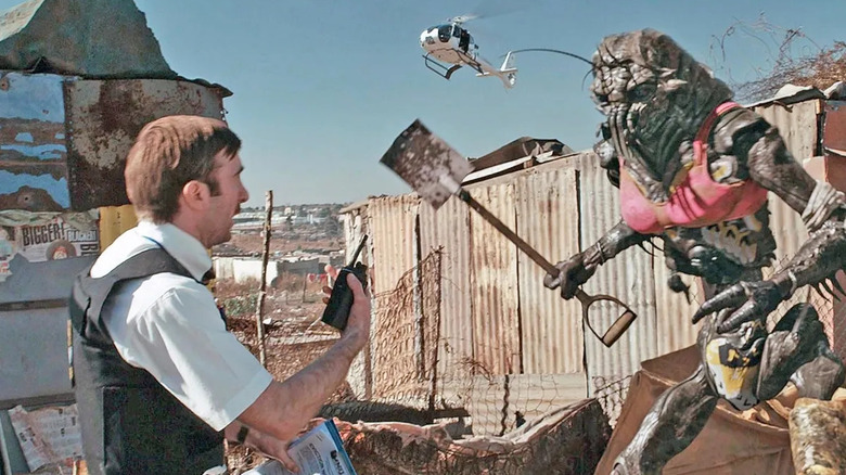 Sharlto Copley as Wikus, standing in front of a prawn in District 9