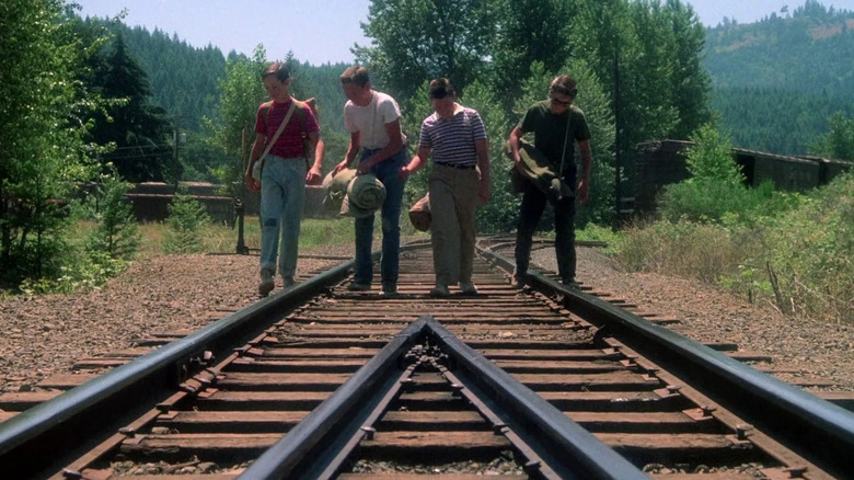 Wil Wheaton as Gordie, River Phoenix as Chris, Corey Feldman as Teddy, and Jerry O'Connell as Vern walk on railroad tracks in Stand By Me.