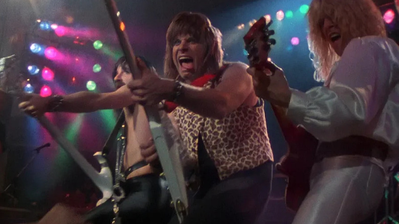 Harry Shearer as Derek Smalls, Christopher Guest as Nigel Tufnel, and Michael McKean as David St. Hubbins performing on stage in This Is Spinal Tap