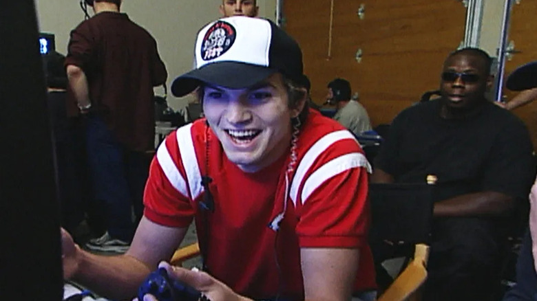 Ashton Kutcher gleefully looks into a monitor with his crew behind him in Punk'd