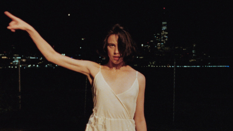 Margaret Qualley dancing against the New York City skyline at night in the Tiny Moves music video