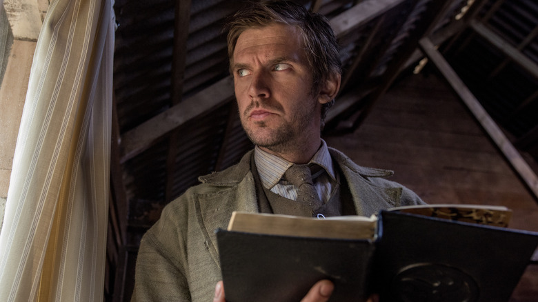 Thomas Richardson (Dan Stevens) holding a book in Apostle