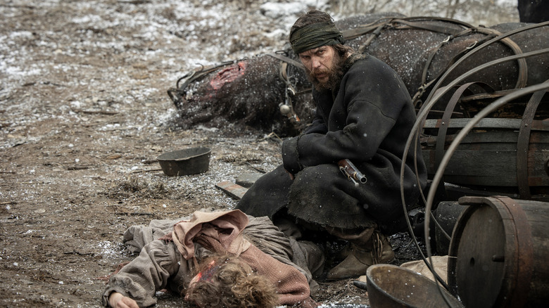 Taylor Kitch as Isaac Reed looking angry and crouching beside a dead body on American Primeval