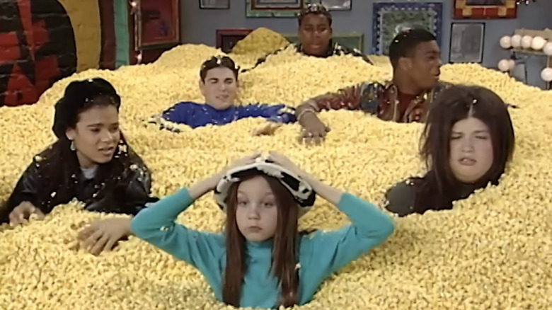 Amanda Bynes, Lori Beth Denberg, Alida Reyes, Josh Server, Kel Mitchell, and Kenan Thompson in All That, all half buried in mounds of popcorn.
