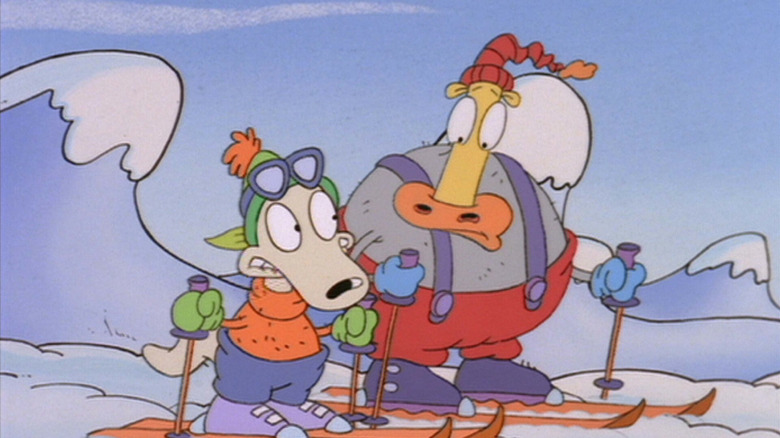 Carlos Alazraqui as Rocko and Mr. Lawrence/ Tom Kenny as Heffer in Rocko's Modern Life, among the snowy mountains in winter gear and on skis.