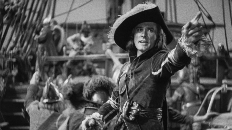 Peter Blood (Errol Flynn) points while on his ship's deck in Captain Blood
