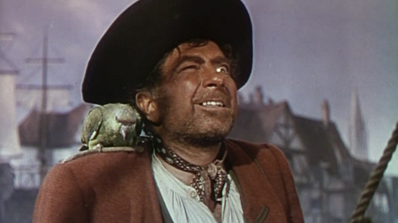 Long John Silver (Robert Newton) sneers with a parrot on his shoulder in Treasure Island (1950)