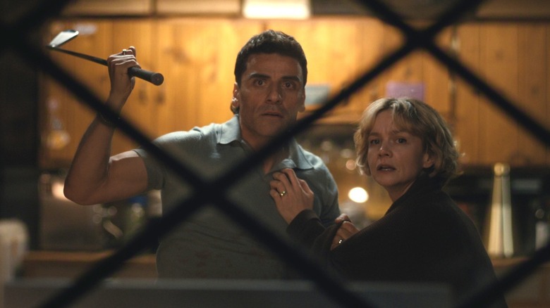 Josh Martin (Oscar Isaac) and Lindsay Crane-Martin (Carey Mulligan) stare out a window while Josh holds a golf club in Beef