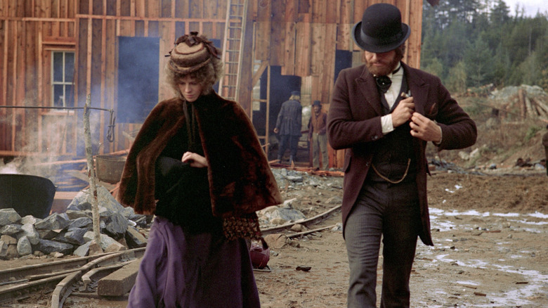 Julie Christie as Constance Miller and Warren Beatty as John McCabe in McCabe & Mrs. Miller, the two walking side-by-side through a frontier town.