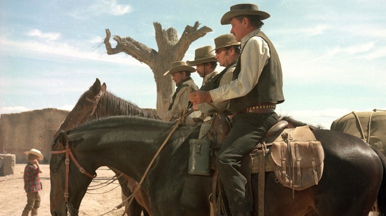 William Holden as Pike Bishop, Ernest Borgnine as "Dutch" Engstrom, Warren Oates as Lyle Gorch, and Ben Johnson as Tector Gorch in The Wild Bunch, mounted on horseback next to each other.