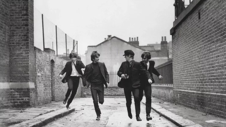 Paul McCartney, George Harrison, Ringo Starr, and John Lennon run down an empty street in A Hard Day's Night