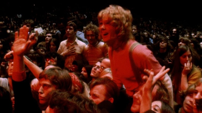 The crowd cheers while bathed in red light in Gimme Shelter (1970)