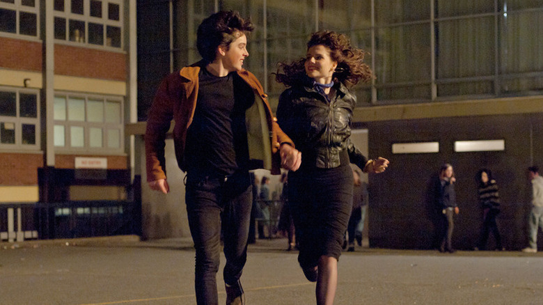 Conor Lalor (Ferdia Walsh-Peelo) and Raphina (Lucy Boynton) hold hands and smile while running in Sing Street