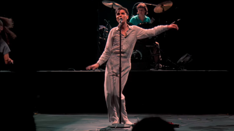 David Byrne waves his arms while singing on stage in Stop Making Sense