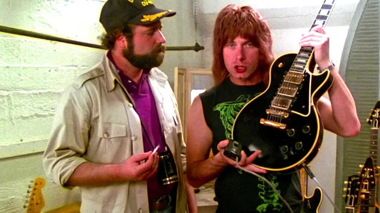Marty Di Bergi (Rob Reiner) watches Nigel Tufnel (Christopher Guest) show off an electric guitar in This Is Spinal Tap
