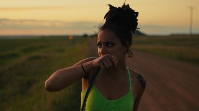 Sasha Lane as Star standing on the open road and wiping her mouth in American Honey